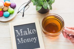 Concept Make Money message on wood boards. Macaroons and glass Tea on table. Vintage tone.